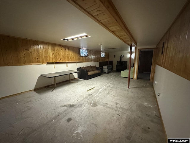 finished below grade area featuring a wood stove and wooden walls