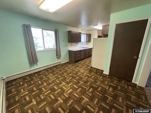 kitchen with freestanding refrigerator, a baseboard heating unit, light countertops, dark brown cabinets, and a sink