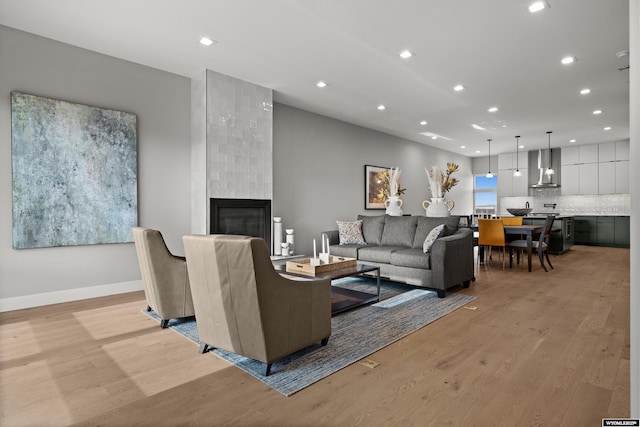 living room with light wood finished floors, recessed lighting, and a tiled fireplace