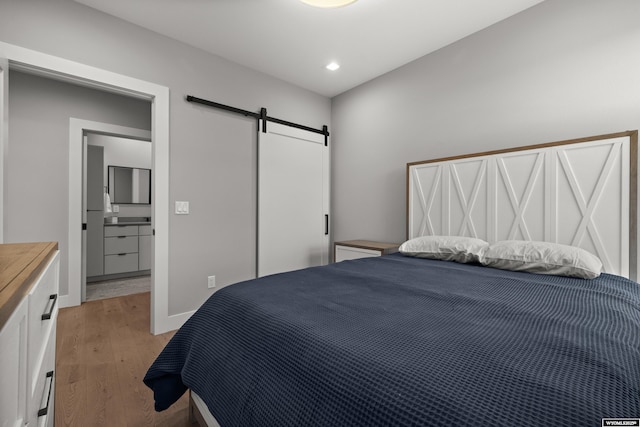 bedroom with a barn door, light wood-type flooring, and recessed lighting