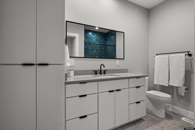 bathroom featuring toilet, vanity, and baseboards