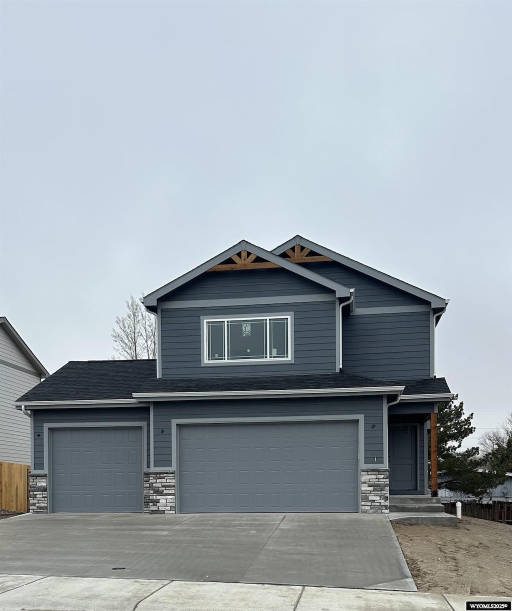 craftsman house with concrete driveway, stone siding, a garage, and fence
