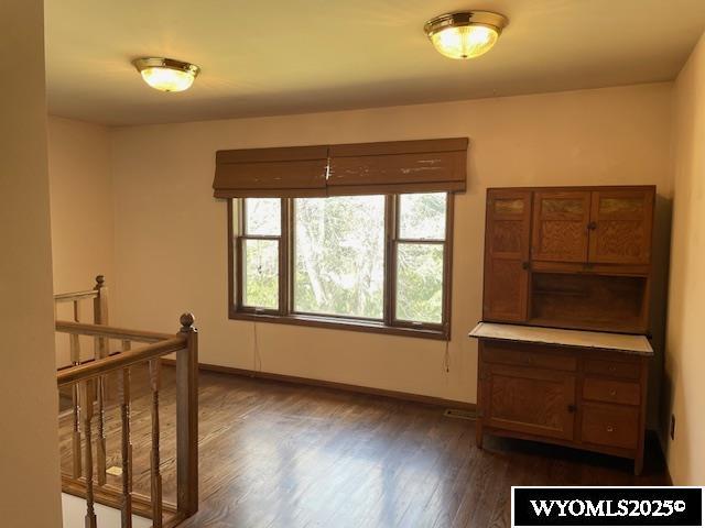unfurnished room featuring dark wood-style flooring and baseboards