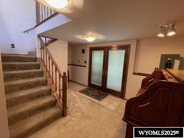doorway featuring light carpet, electric panel, stairway, and french doors