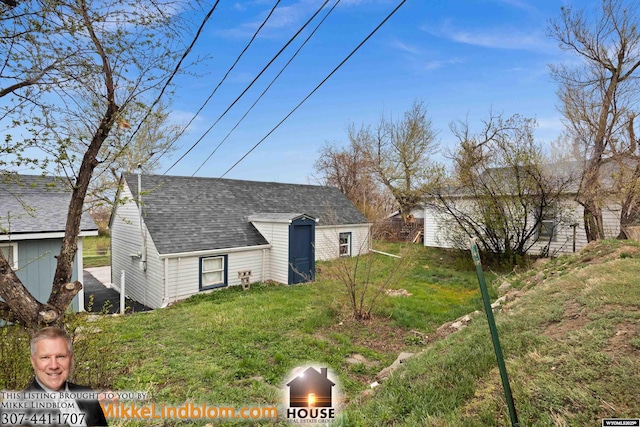 view of front of property with an outdoor structure, roof with shingles, and a front lawn