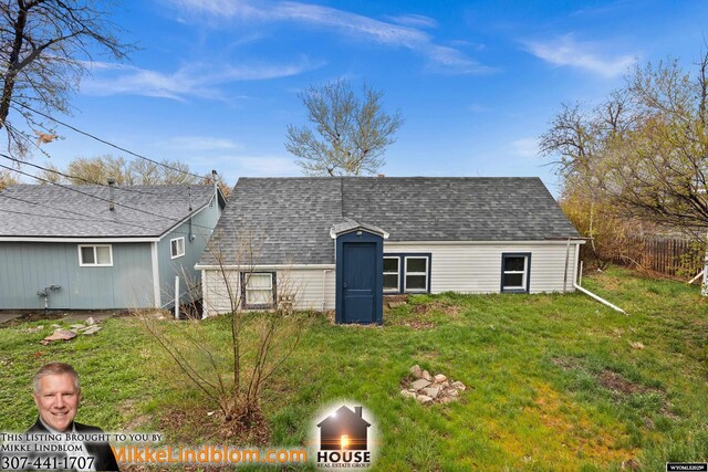 back of house with a yard and roof with shingles