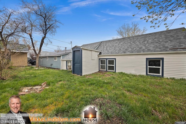 rear view of property featuring roof with shingles and a yard