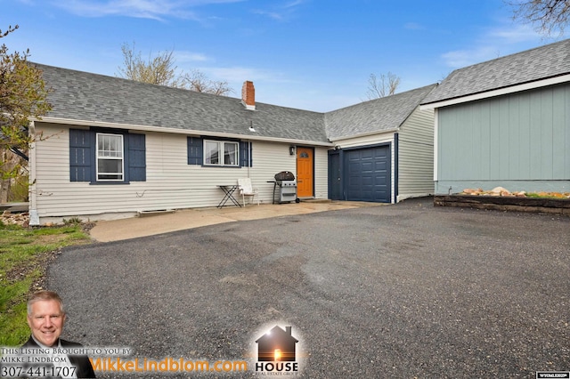 view of front of home featuring a chimney, an attached garage, driveway, and a shingled roof