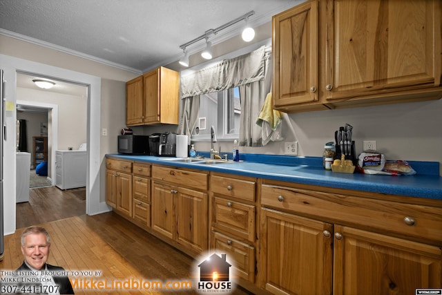 kitchen featuring a sink, dark wood-style flooring, brown cabinetry, ornamental molding, and a textured ceiling