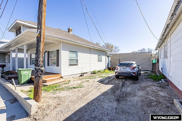 330 M St, Rock Springs, WY 82901 - view of side of home with a porch, a chimney, and roof with shingles