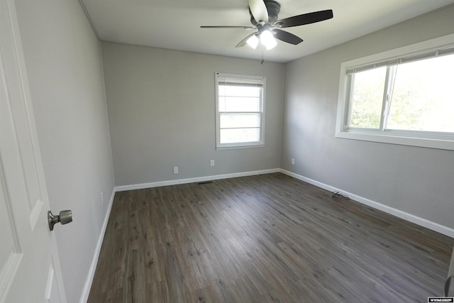 unfurnished room featuring dark wood finished floors, a ceiling fan, and baseboards