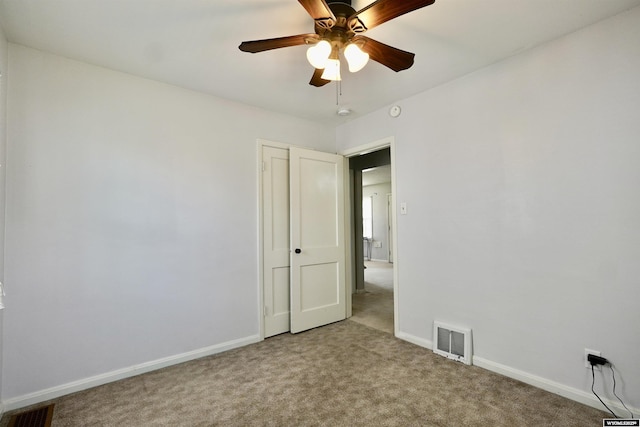 carpeted spare room featuring baseboards and a ceiling fan
