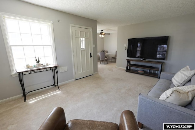 carpeted living room featuring a ceiling fan, baseboards, and a textured ceiling