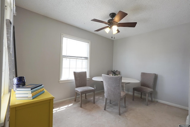 dining space featuring ceiling fan, light carpet, a textured ceiling, and baseboards