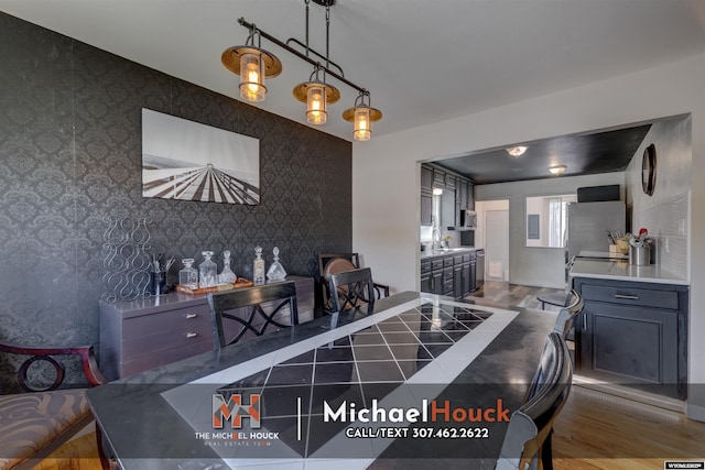 dining space with wallpapered walls, wood finished floors, and an accent wall