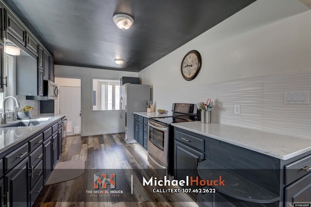 kitchen with a sink, appliances with stainless steel finishes, decorative backsplash, and dark wood-style floors