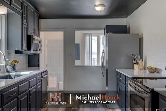 kitchen featuring stainless steel appliances, a sink, light countertops, and wood finished floors