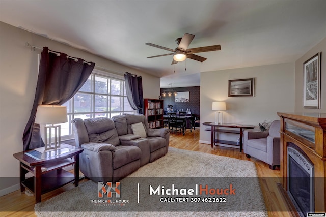 living area with ceiling fan, wood finished floors, a chandelier, and baseboards