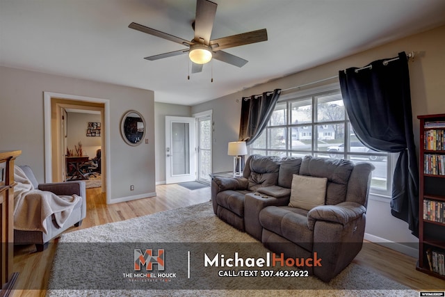 living area with a ceiling fan, wood finished floors, and baseboards