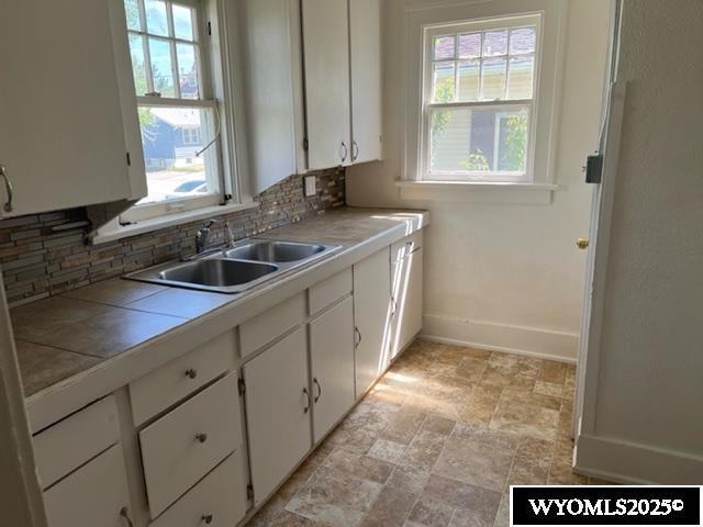 kitchen featuring a sink, tile counters, backsplash, and healthy amount of natural light