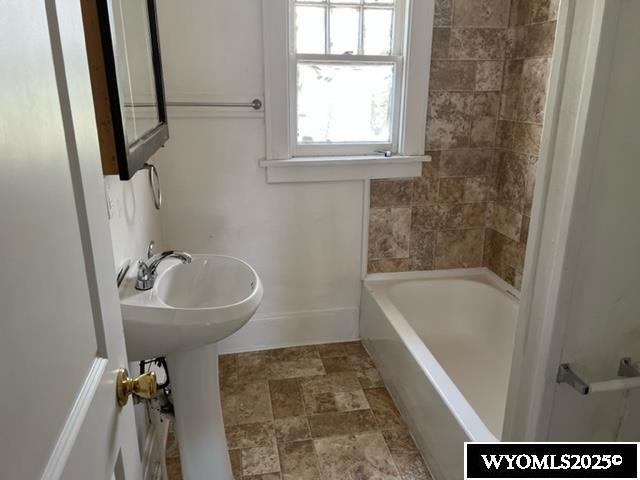 full bath with stone finish flooring and baseboards