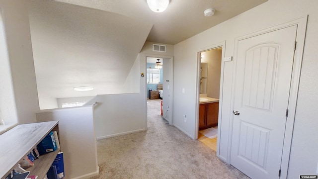 hallway featuring light carpet, an upstairs landing, and baseboards