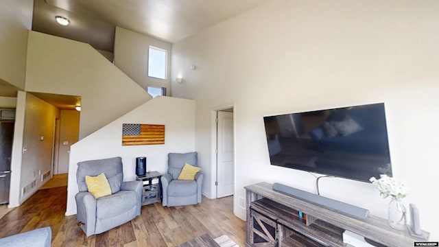 sitting room with wood finished floors and a towering ceiling