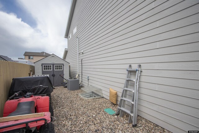 view of side of property with a storage shed, fence, an outdoor structure, and central air condition unit