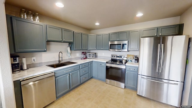 kitchen featuring stainless steel appliances, a sink, light stone countertops, and recessed lighting