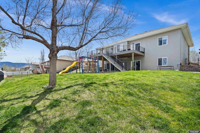 rear view of house with a playground, a deck, and stairs