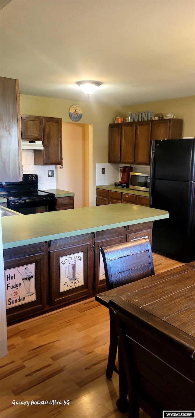 1630 De Smet Ave, Sheridan, WY 82801 - kitchen with black appliances, under cabinet range hood, decorative backsplash, and light wood-style floors