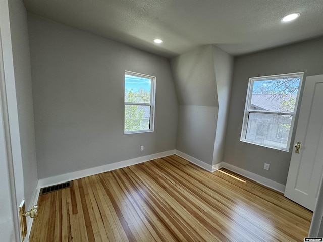 bonus room with plenty of natural light, wood finished floors, baseboards, recessed lighting, and a textured ceiling