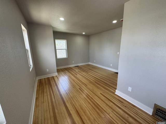 unfurnished room featuring baseboards, light wood finished floors, and recessed lighting