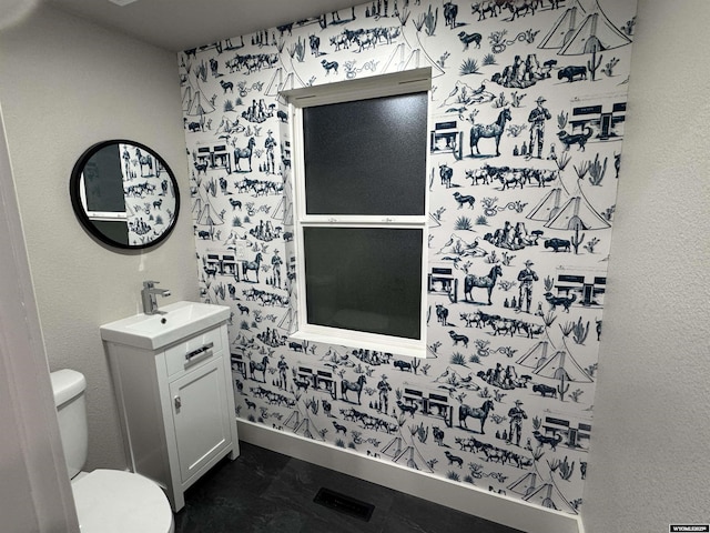 bathroom featuring toilet, baseboards, and vanity