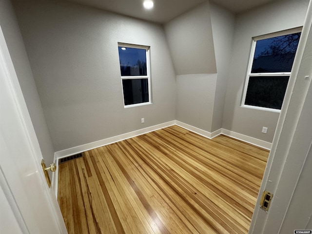 additional living space featuring baseboards and wood finished floors