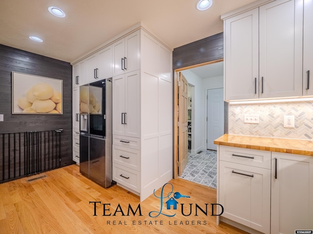 kitchen with refrigerator with ice dispenser, light wood-style flooring, wooden counters, white cabinetry, and recessed lighting
