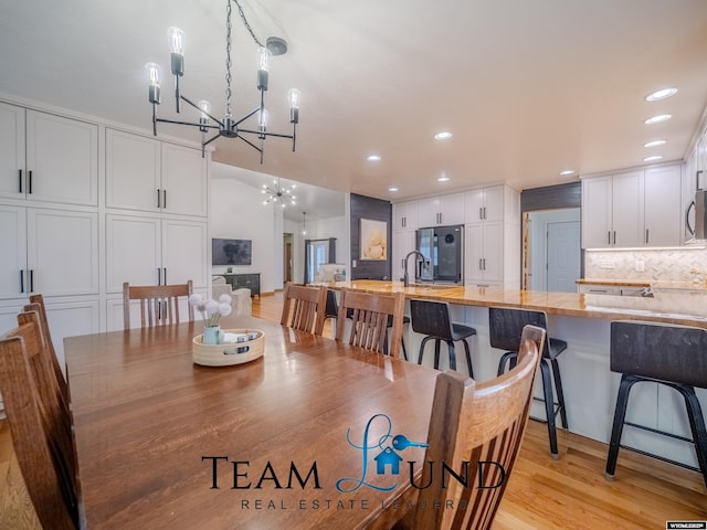 dining area with a chandelier, light wood finished floors, and recessed lighting