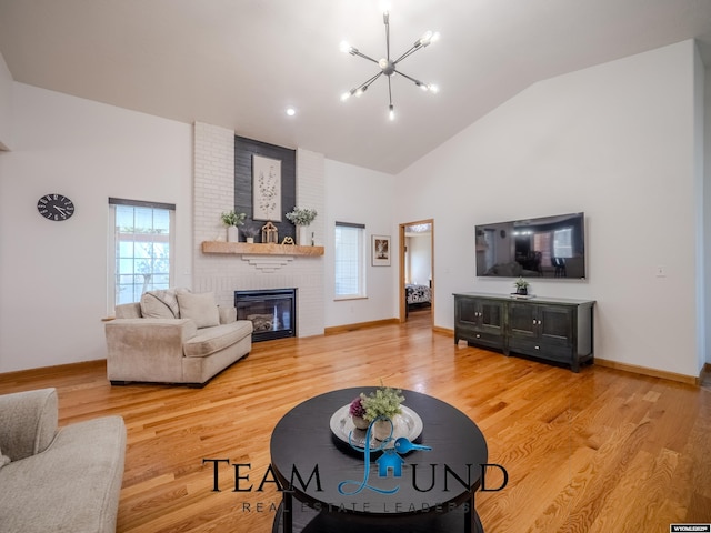 living room with a chandelier, high vaulted ceiling, a fireplace, light wood-type flooring, and baseboards