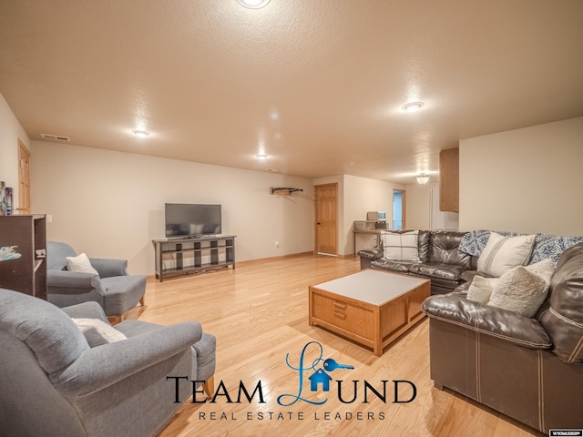 living area with light wood-style floors and a textured ceiling