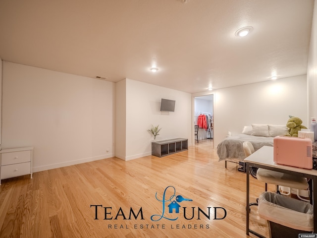 bedroom featuring wood finished floors, a spacious closet, and baseboards