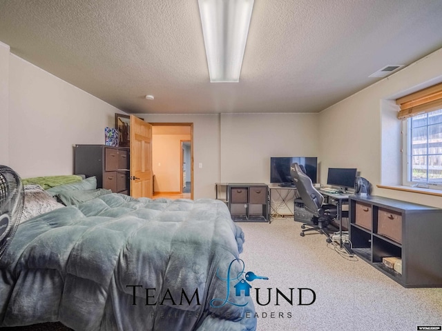 bedroom with a textured ceiling, a desk, and carpet floors