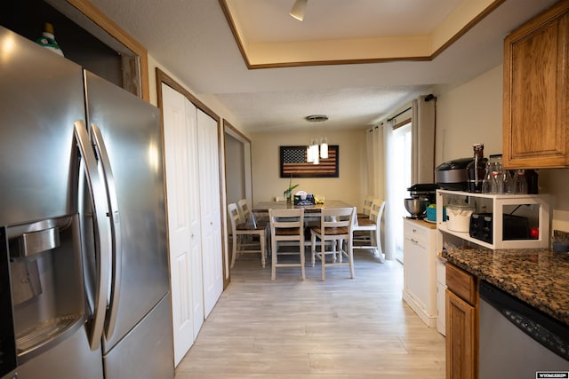 108 Cherokee Ct, Evanston, WY 82930 - kitchen with appliances with stainless steel finishes, brown cabinets, light wood-style floors, a tray ceiling, and decorative light fixtures