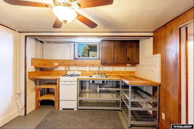 223 S Thurmond St, Sheridan, WY 82801 - kitchen with white gas range, a sink, ceiling fan, and wood walls