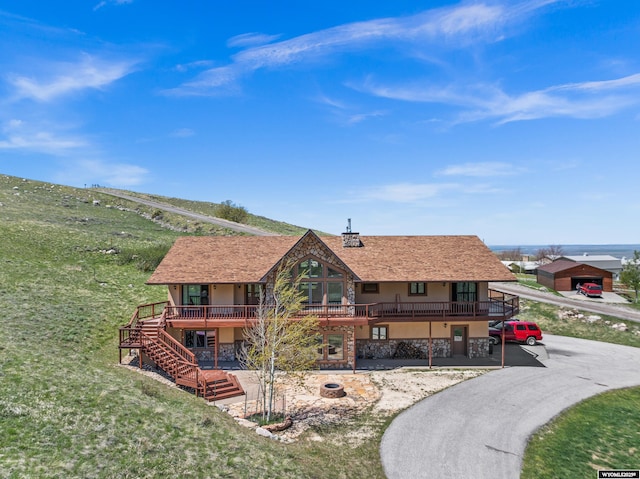 rear view of house featuring stairs, stucco siding, a deck, and a fire pit