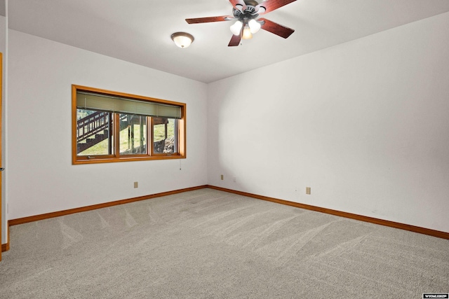 empty room featuring carpet flooring, baseboards, and a ceiling fan