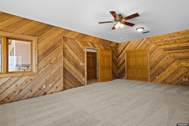bonus room featuring wooden walls, carpet floors, and ceiling fan