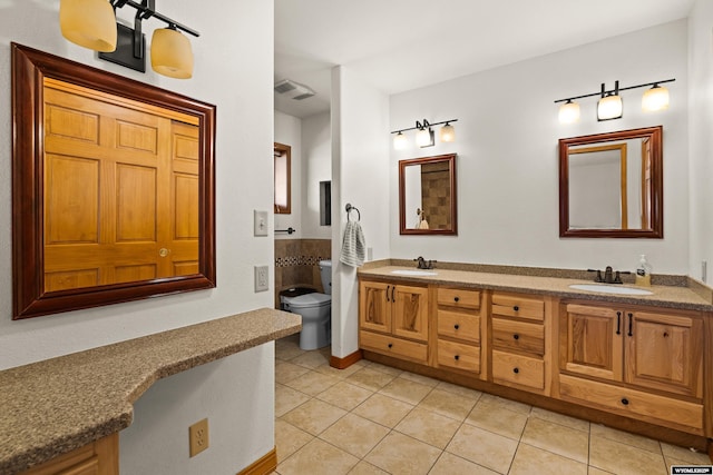bathroom featuring tile patterned flooring, toilet, and double vanity