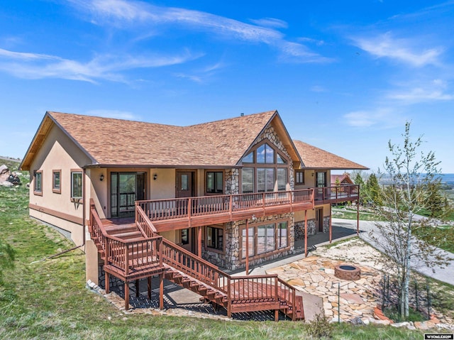 back of house featuring stucco siding, stairs, a wooden deck, a fire pit, and a patio area