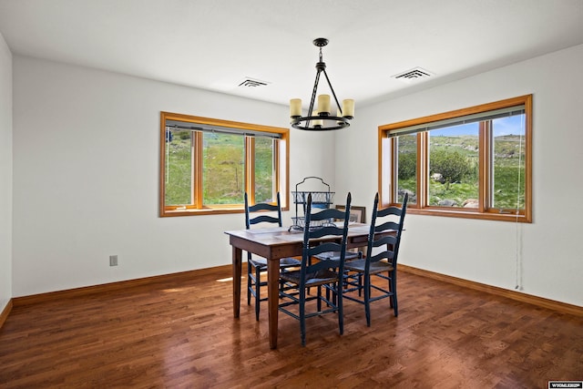 dining area with a chandelier, healthy amount of natural light, and dark wood finished floors