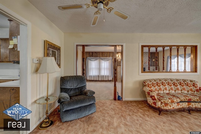 living area with carpet floors, a ceiling fan, a textured ceiling, and baseboards